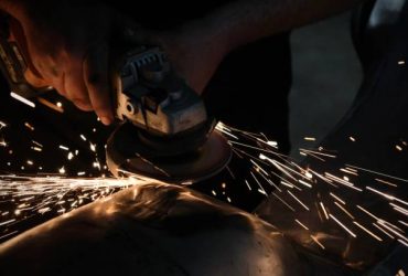 Man grinding a metal motorcycle tank